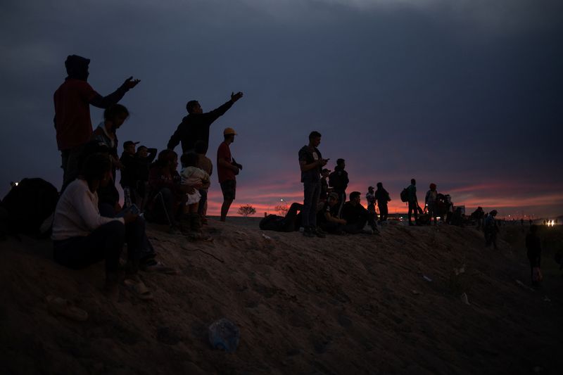 © Reuters. Migrants from South and Central America point towards the United States as they stand atop the bank of the Rio Grade river while searching for an entry point into El Paso, Texas, U.S., from Ciudad Juarez, Mexico, April 24, 2024. REUTERS/Adrees Latif/File Photo