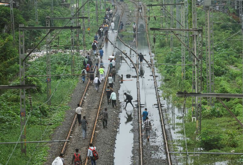 &copy; Reuters. Pessoas caminham em linha do trem atingida por inundação em Mumbain8/07/2024nREUTERS/Francis Mascarenhas