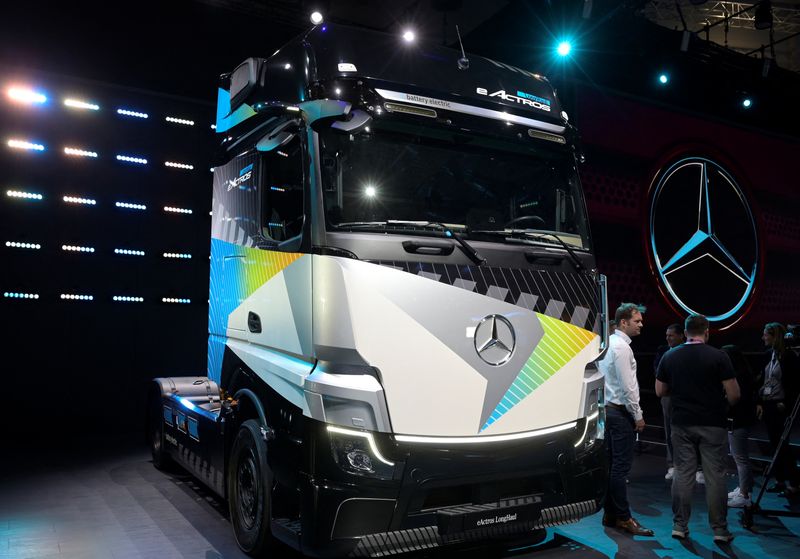 © Reuters. Members of the media stand beside an electric driven Actros truck at the booth of German truckmaker Daimler Truck at the IAA Transportation fair, which will open its doors to the public on September 20, 2022, in Hanover, Germany, September 19, 2022. REUTERS/Fabian Bimmer/File Photo