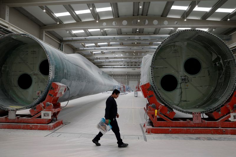 &copy; Reuters. Una persona cammina mentre gli operai costruiscono pale di turbine eoliche nella fabbrica di pale Nordex a Lumbier, Spagna, 18 marzo 2024. Foto REUTERS/Vincent West