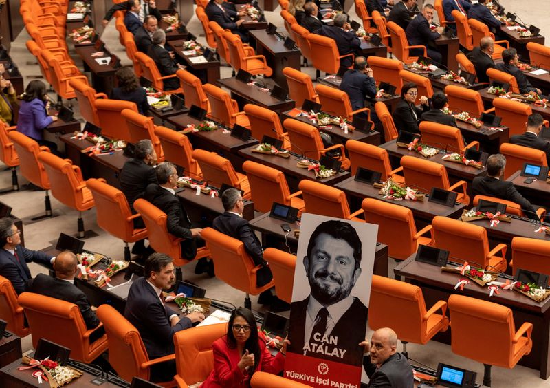 © Reuters. Erkan Bas, the leader of Workers' Party of Turkey (TIP) and his party MPs Sera Kadigil and Ahmet Sik display a portrait of Can Atalay, a jailed MP of TIP, during a swearing-in ceremony at the Turkish parliament in Ankara, Turkey, June 2, 2023. Atalay has not been released despite a law that opens a way for jailed politicians to be released from prison if they are elected to parliament. REUTERS/Umit Bektas/File Photo