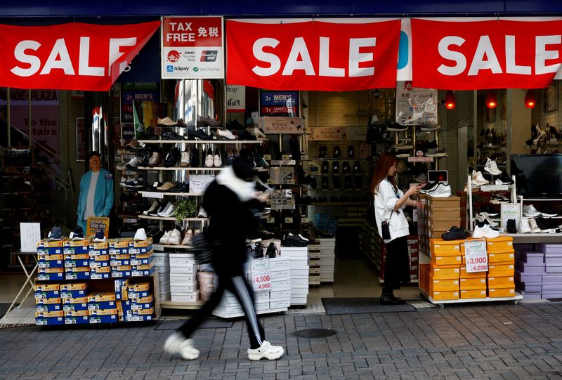 © Reuters. FILE PHOTO: A passerby walks past a retail shop displaying 'SALE' banners in Tokyo, Japan,  February 15, 2024.  REUTERS/Issei Kato/File Photo