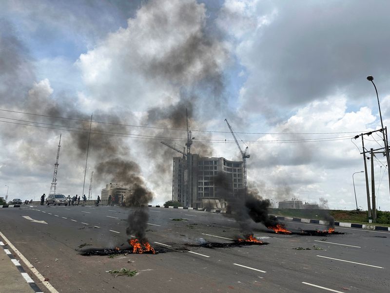 © Reuters. Smoke rises from the burnt tires on a street, while demonstrators check the vehicles during an anti-government demonstration to protest against bad governance and economic hardship in Abuja, Nigeria August 1, 2024. REUTERS/Abraham Achirga