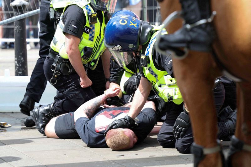 © Reuters. Police officers detain an anti-immigration demonstrator during a protest in Manchester, Britain, August 3, 2024. REUTERS/Manon Cruz    