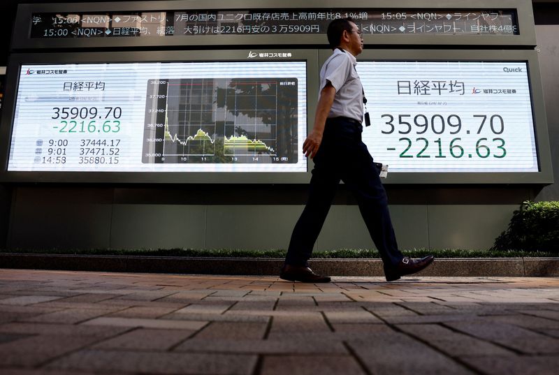 © Reuters. A man walks past electronic screens displaying Japan's Nikkei share average outside a brokerage in Tokyo, Japan August 2, 2024. REUTERS/Issei Kato/File Photo