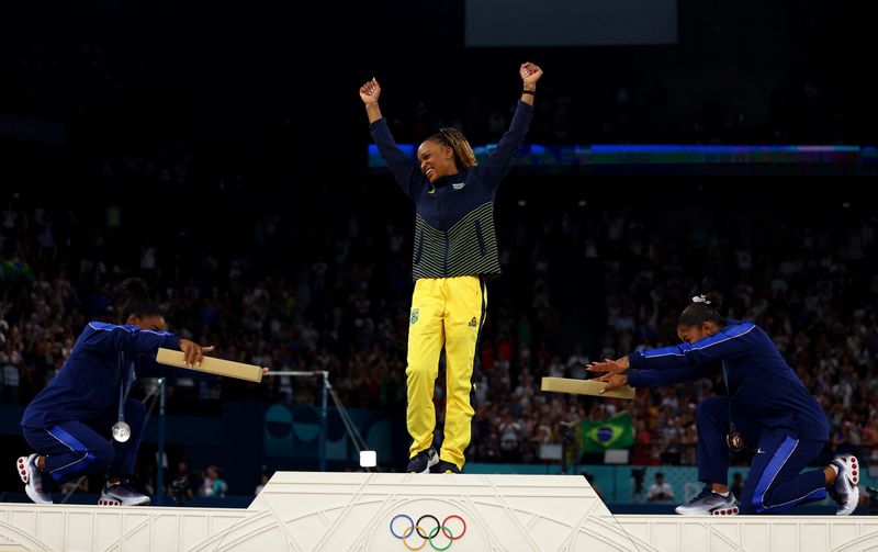 © Reuters. Norte-americanas Simone Biles e Jordan Chiles reverenciam Rebeca Andrade no pódio após brasileira conquistar medalha de ouro no solo na Olimpíada Paris 2024
05/08/2024 REUTERS/Hannah Mckay