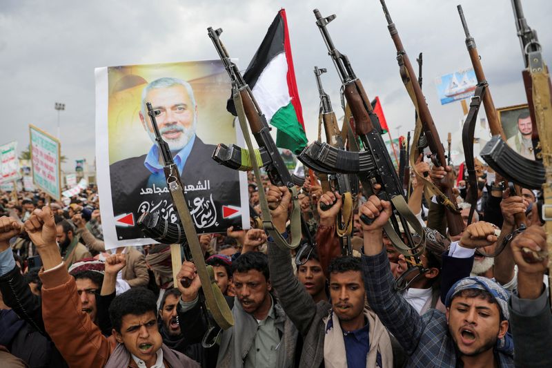 © Reuters. FILE PHOTO: Protesters, mainly Houthi supporters, hold firearms next to a poster of assassinated Hamas chief Ismail Haniyeh, at the rally to show solidarity with Palestinians in the Gaza Strip, in Sanaa, Yemen, August 2, 2024. REUTERS/Khaled Abdullah/File Photo