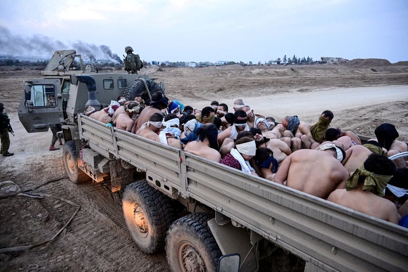 © Reuters. FILE PHOTO: Israeli soldiers stand by a truck packed with shirtless Palestinian detainees, amid the ongoing conflict between Israel and the Palestinian Islamist group Hamas, in the Gaza Strip December 8, 2023.  REUTERS/Yossi Zeliger/File Photo