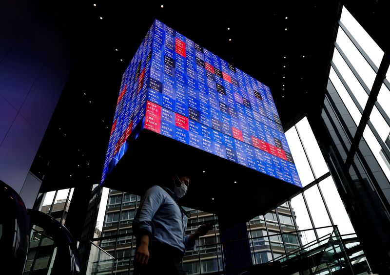 © Reuters. FILE PHOTO: A man walks under an electronic screen showing Japan's Nikkei share price index inside a conference hall in Tokyo, Japan June 14, 2022. REUTERS/Issei Kato/File Photo