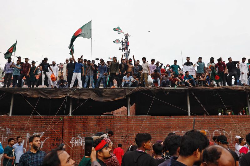 &copy; Reuters. People waves Bangladeshi flags on top of the Ganabhaban, the Prime Minister's residence, as they celebrate the resignation of PM Sheikh Hasina in Dhaka, Bangladesh, August 5, 2024. REUTERS/Mohammad Ponir Hossain