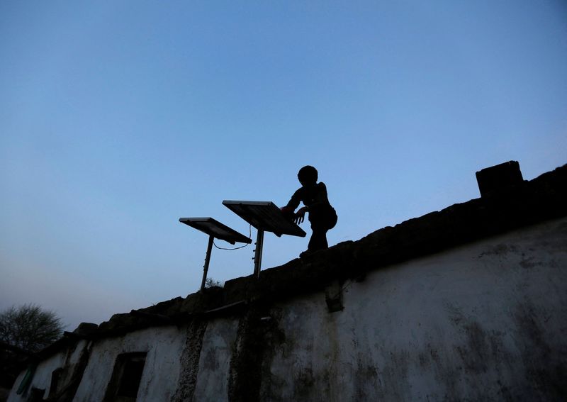 © Reuters. FILE PHOTO: A boy dusts off a solar panel installed on the rooftop of his house on the outskirts of the western Indian city of Ahmedabad October 27, 2014. INDIA-SOLAR//File Photo