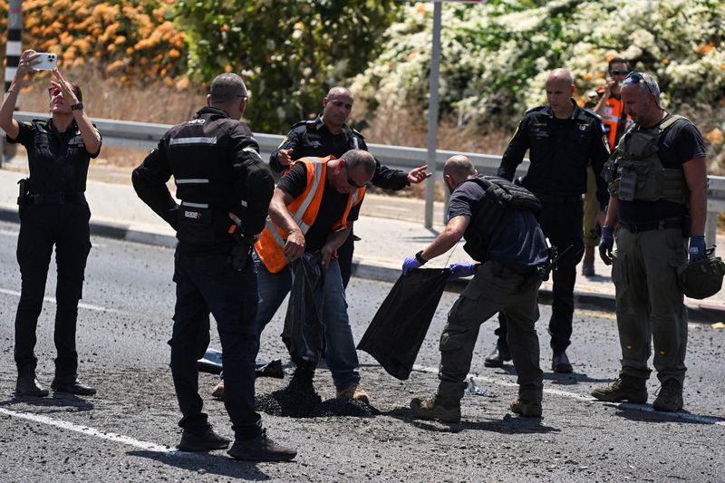 © Reuters. Israeli police and officials work at the impact site of a projectile, after Lebanon's armed group Hezbollah said it launched a swarm of attack drones against military targets in northern Israel, in Nahariya, Israel, August 6, 2024. REUTERS/Rami Shlush   