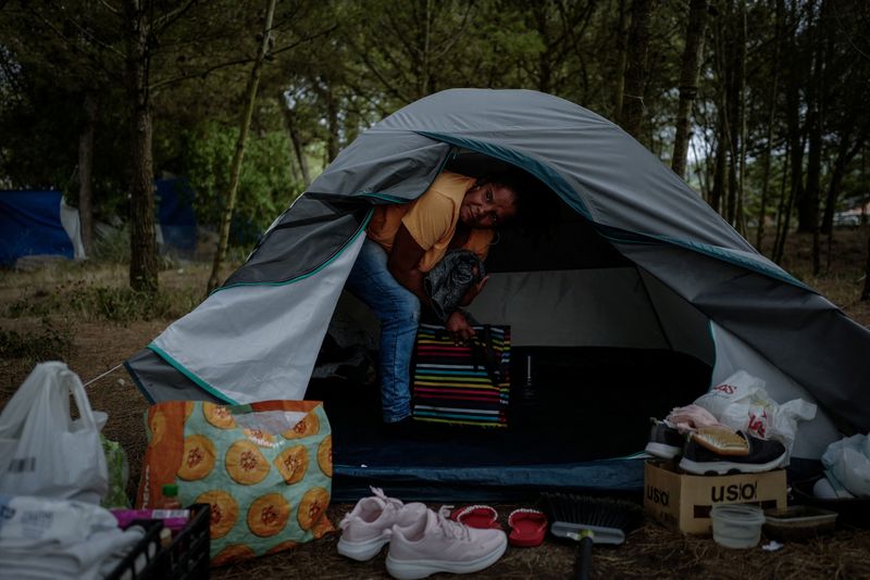 © Reuters. Andreia Costa, 50, from Sao Paulo, Brazil, takes belongings out of a tent, as she cleans at the improvised campsite in a field where she lives in Carcavelos, in Cascais, Portugal, October 11, 2023. Seeking a more comfortable life, Costa moved to Portugal from Brazil in 2022, but within months her hopes were dashed, as the country's housing crisis left her unable to afford accommodation and forced to live in a tent. On a site on the outskirts of Lisbon she was joined by other migrants and some locals, priced out of a city where rents have soared 94 percent since 2015 and house prices have risen 186 percent, according to housing data specialists Confidencial Imobiliario.       REUTERS/Pedro Nunes      