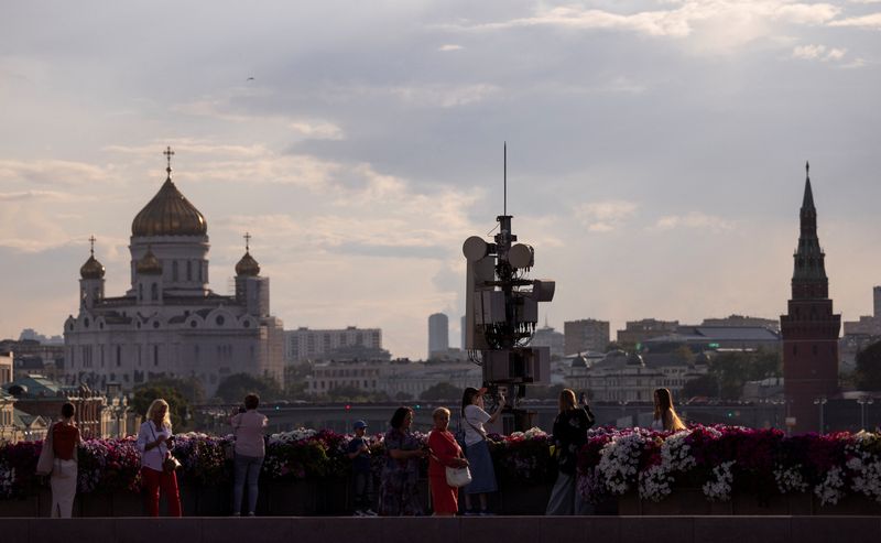 &copy; Reuters. Persone su un ponte con vista sulla Cattedrale di Cristo Salvatore, sulle torri del Cremlino e sullo skyline della città a Mosca, in Russia, il 5 agosto 2024. REUTERS/Maxim Shemetov