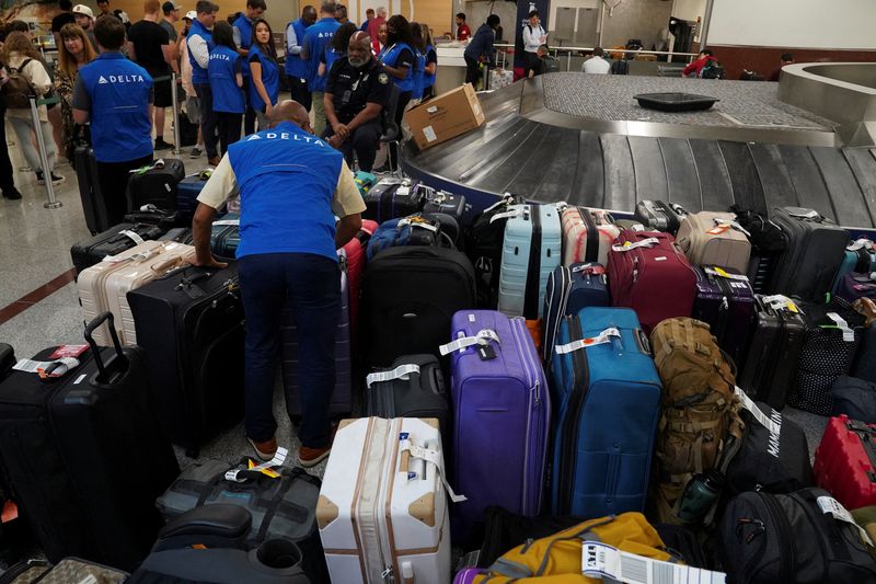 &copy; Reuters. FILE PHOTO: Delta employees are seen near luggage, as people wait to retrieve their luggage after long delays following cyber outages affecting airlines at Hartsfield-Jackson Atlanta International Airport in Atlanta, Georgia, U.S., July 22, 2024.   REUTER