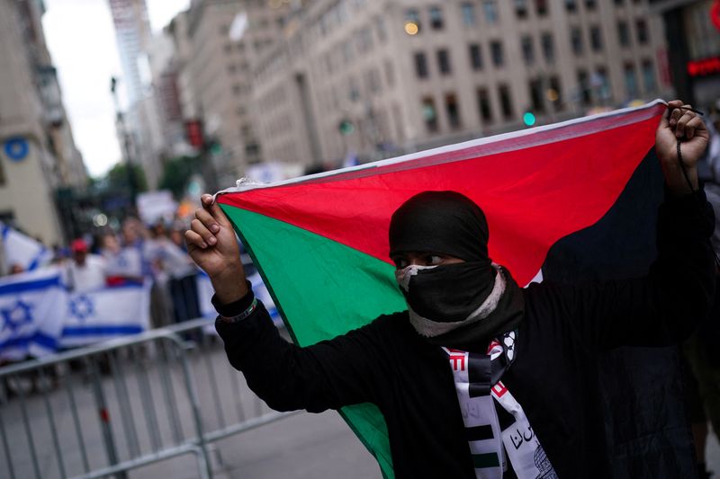 © Reuters. FILE PHOTO: A pro-Palestinian supporter holds a Palestinian flag as people protest against City University of New York, CUNY college allowing the filming of an FBI: Most Wanted episode fictionalising a Gaza Solidarity Encampment in New York City, U.S., July 22, 2024. REUTERS/Adam Gray/File Photo