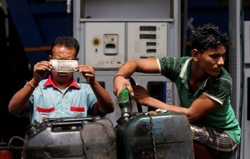 © Reuters. FILE PHOTO: A worker checks a 500 Indian rupee note as a man fills diesel in containers at a fuel station in Kolkata, India, August 14, 2018. REUTERS/Rupak De Chowdhuri/File Photo