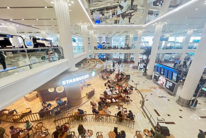 &copy; Reuters. FILE PHOTO: People sit at a coffee shop as they wait for their flight after a rainstorm hits Dubai, causing delays at the Dubai International Airport, in Dubai, United Arab Emirates, April 17, 2024. REUTERS/Staff/File Photo