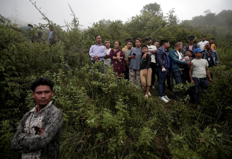 © Reuters. People watch as security force personnel prepare to carry the bodies of the victims at the site of a helicopter crash on the outskirts of Kathmandu, Nepal, August 7, 2024. REUTERS/Navesh Chitrakar