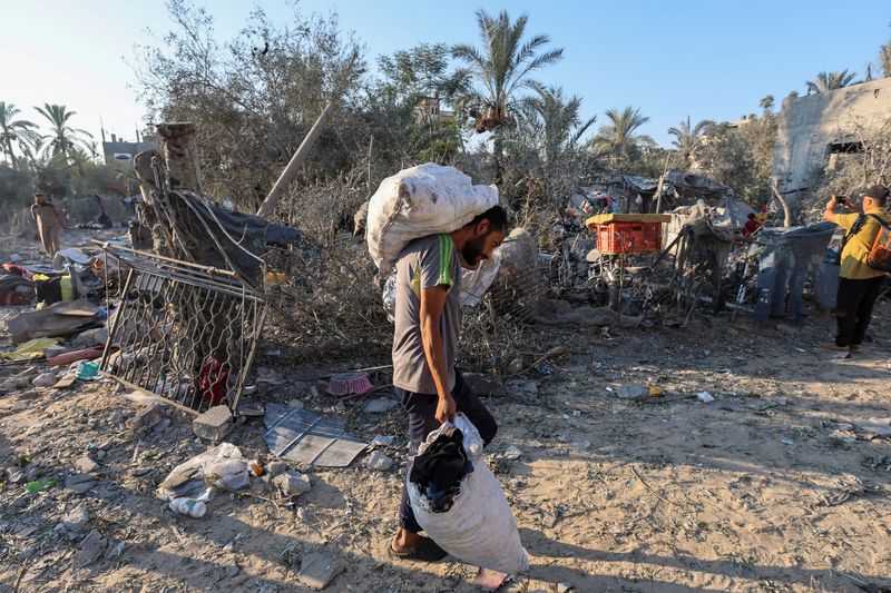 &copy; Reuters. Un uomo palestinese trasporta le proprie cose sul luogo di un attacco israeliano che ha danneggiato una tendopoli per sfollati, durante il conflitto tra Israele e Hamas, a Deir Al-Balah, nella Striscia di Gaza centrale, il 7 agosto 2024. REUTERS/Ramadan A