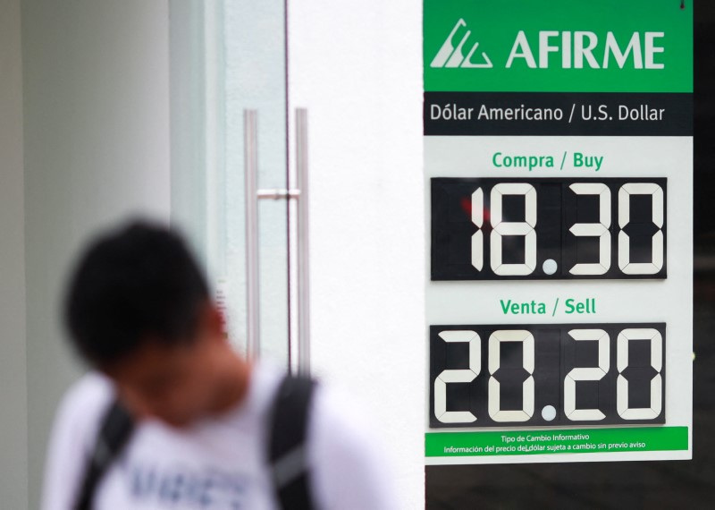 © Reuters. A man walks past a board showing the exchange rates of the Mexican peso against the U.S. dollar, at a bank in Mexico City, Mexico August 6, 2024.REUTERS/Henry Romero