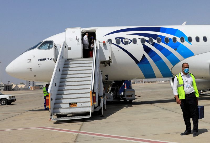 © Reuters. FILE PHOTO: An employee of Luxor's International Airport, wearing a protective face mask, walks next to an EgyptAir plane in Luxor, Egypt April 9, 2021. REUTERS/Amr Abdallah Dalsh/File Photo