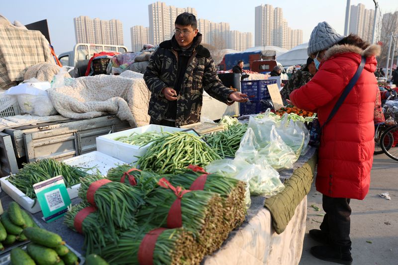 &copy; Reuters. FILE PHOTO: A vegetable vendor collects money from a customer at an outdoor market in Beijing, China January 12, 2024. REUTERS/Florence Lo/File Photo