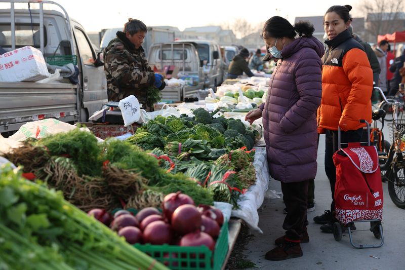 © Reuters. FILE PHOTO: A woman looks at vegetables displayed at a stall at an outdoor market in Beijing, China January 12, 2024. REUTERS/Florence Lo/File Photo