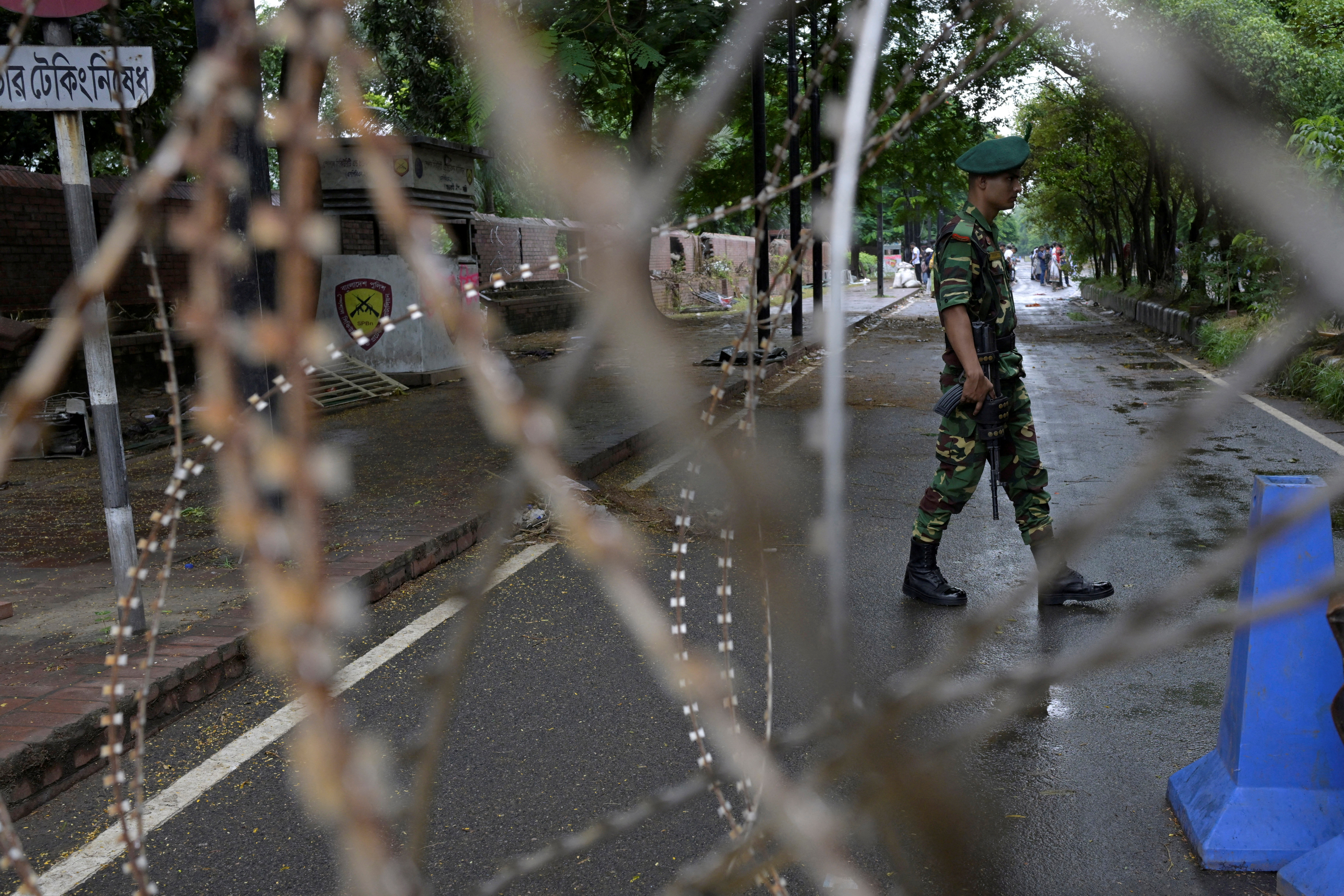 © Reuters. FILE PHOTO: A security force personnel walks behind concertina wire placed across a road next to the residence of former Bangladeshi Prime Minister Sheikh Hasina, days after her resignation as the prime minister of the country, in Dhaka, Bangladesh, August 8, 2024. REUTERS/Fatima Tuj Johora/File Photo