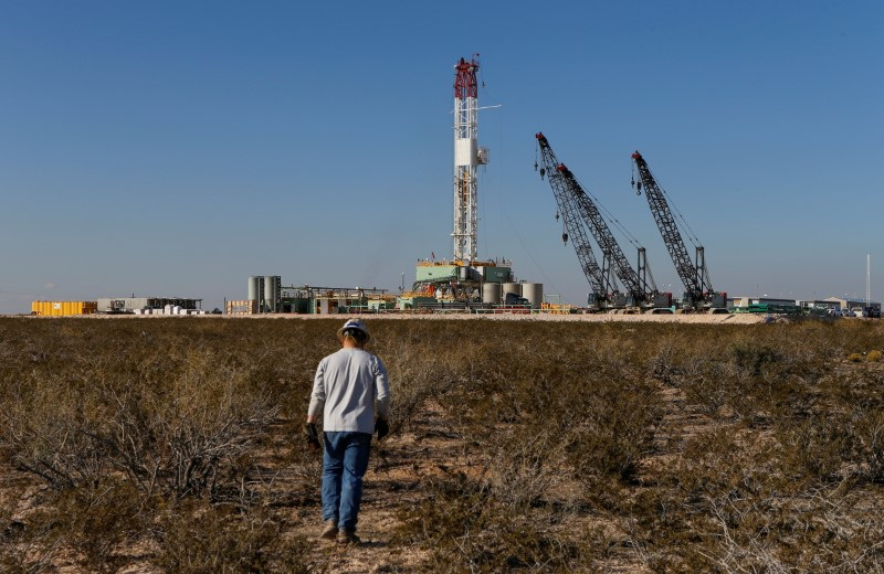 &copy; Reuters. Un lavoratore del settore petrolifero cammina verso un impianto di trivellazione dopo aver posizionato le apparecchiature di monitoraggio del terreno in prossimità della trivellazione orizzontale sotterranea nella Contea di Loving, Texas, Stati Uniti, 22