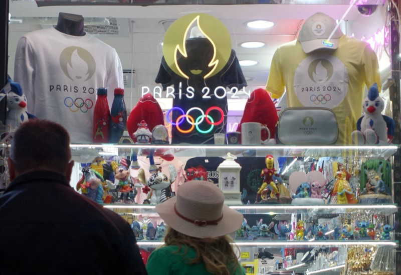 © Reuters. FILE PHOTO: People look at a display at a shop at Champs-Elysees with souvenirs advertising the Paris 2024 Olympic and Paralympic Games in Paris, France, July 6, 2024. REUTERS/Fabrizio Bensch/File Photo