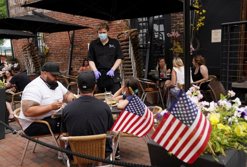 © Reuters. FILE PHOTO: A waiter serves diners seated outdoors at a restaurant in Alexandria, Virginia, U.S., May 29, 2020. REUTERS/Kevin Lamarque/File photo