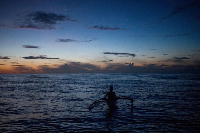 © Reuters. FILE PHOTO: A Filipino fisheman rows a boat during a trip near the disputed Scarborough Shoal, in Masinloc, Zambales province, Philippines, July 18, 2022.  REUTERS/Lisa Marie David/File Photo