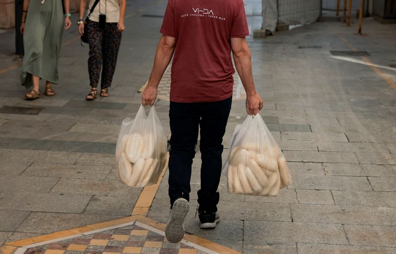 © Reuters. FILE PHOTO: A waiter carries plastic bags with bread along a street in Ronda, Spain, July 24, 2024. REUTERS/Jon Nazca/File Photo