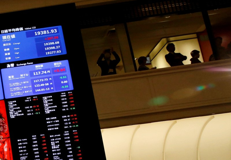 © Reuters. FILE PHOTO: People are seen behind an electronic board showing stock prices after the New Year opening ceremony at the Tokyo Stock Exchange (TSE), held to wish for the success of Japan's stock market, in Tokyo, Japan, January 4, 2017. REUTERS/Kim Kyung-Hoon/File photo