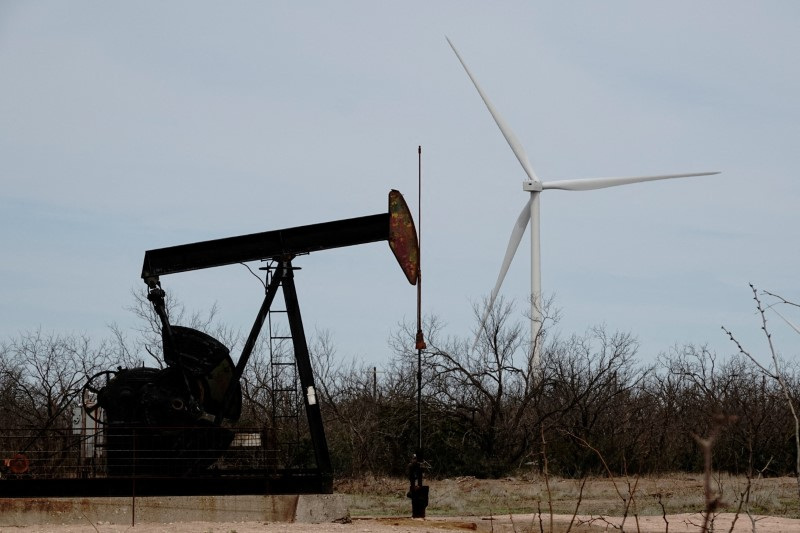 © Reuters. FILE PHOTO: A pump jack drills crude oil from the Yates field in the Permian Basin of West Texas, while a 1.5 MW GE wind turbine at the Desert Sky Wind Farm is seen in the distance near Iraan, Texas, USA, March 17, 2023. REUTERS/Bing Guan/File photo