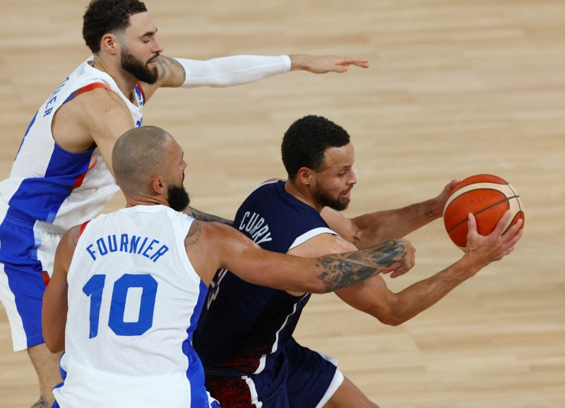 © Reuters. FILE PHOTO: Paris 2024 Olympics - Basketball - Men's Gold Medal Game - France vs United States - Bercy Arena, Paris, France - August 10, 2024. Stephen Curry of United States in action with Evan Fournier of France and Isaia Cordinier of France. REUTERS/Stephanie Lecocq/File Photo