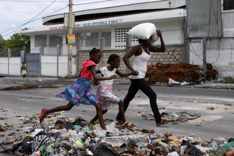 &copy; Reuters. Mulher com dois filhos carrega seus pertences enquanto moradores de Lower Delmas fogem de suas casas devido à violência de gangues, em Porto Príncipe, Haitin02/05/2024nREUTERS/Ralph Tedy Erol