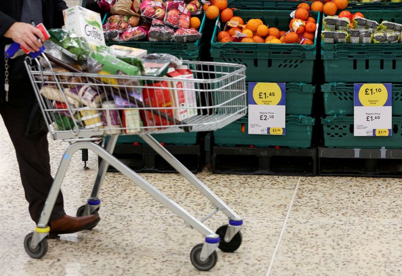 © Reuters. FILE PHOTO: A person pushes a shopping cart next to the clubcard price branding inside a branch of a Tesco Extra Supermarket in London, Britain, February 10, 2022. REUTERS/Paul Childs/File Photo