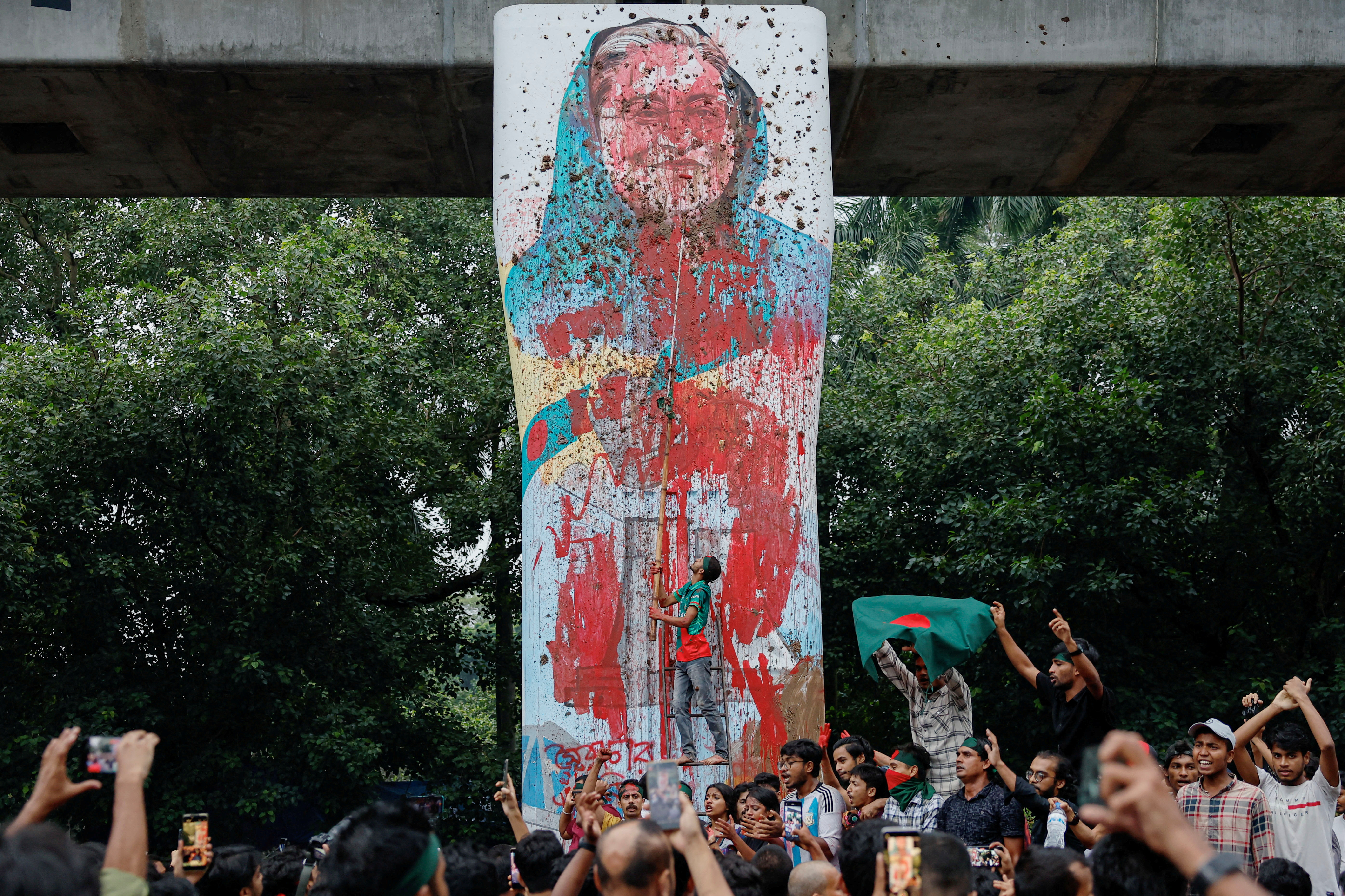 © Reuters. FILE PHOTO: Protesters shout slogans as they vandalise a mural of Bangladeshi Prime Minister Sheikh Hasina with paint and mud, demanding her resignation at Teacher Student Center (TSC) area of University of Dhaka in Dhaka, Bangladesh, August 3, 2024. REUTERS/Mohammad Ponir Hossain/File Photo