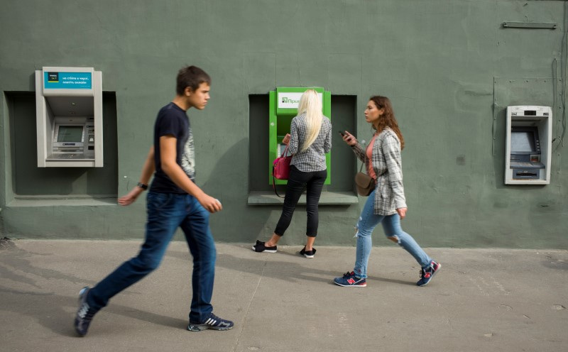 © Reuters. A woman uses an ATM machine as people walk past in central Kharkiv, Ukraine September 18, 2018. Picture taken September 18, 2018.  REUTERS/Gleb Garanich/ File Photo