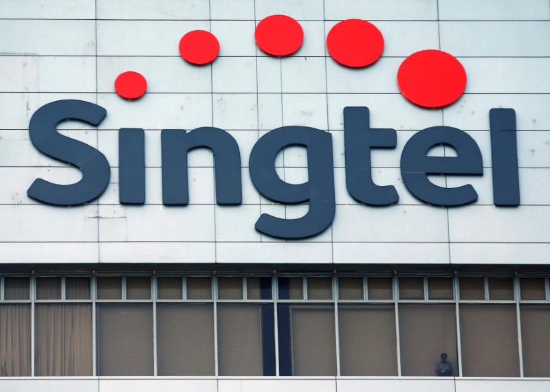 &copy; Reuters. FILE PHOTO A man looks out of the window under a Singtel signage at their head office in Singapore February 12, 2015.  REUTERS/Edgar Su/File Photo 