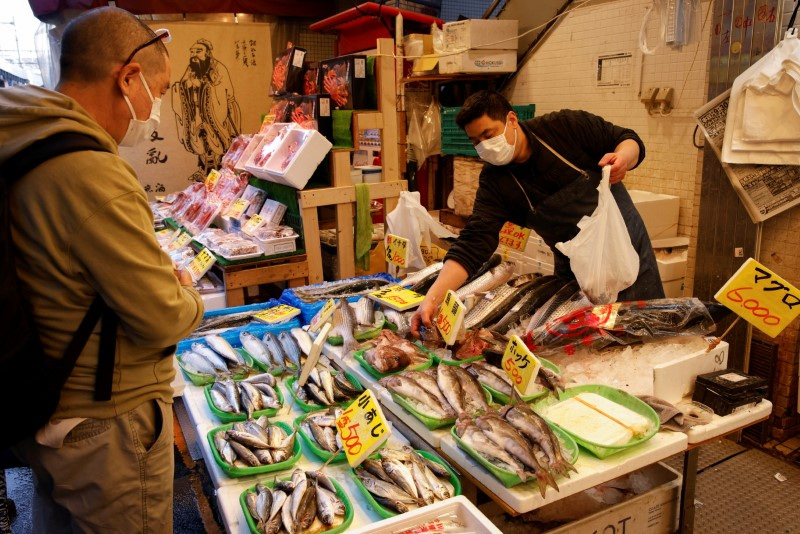 © Reuters. FILE PHOTO: A man buys fish at a market in Tokyo, Japan March 3, 2023. REUTERS/Androniki Christodoulou/File Photo