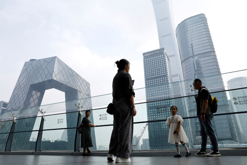 © Reuters. FILE PHOTO: People stand at a shopping mall near CCTV headquarters and the China Zun skyscraper in the central business district (CBD) of Beijing, China, September 7, 2023. REUTERS/Tingshu Wang/File Photo