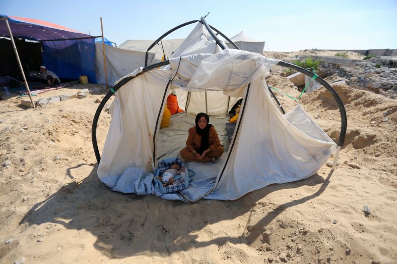 © Reuters. A displaced Palestinian woman and a child shelter in a cemetery, as Gaza health ministry announced that death toll has surpassed 40,000, amid the Israel-Hamas conflict, in Khan Younis, in the southern Gaza Strip, August 15, 2024. REUTERS/Hatem Khaled