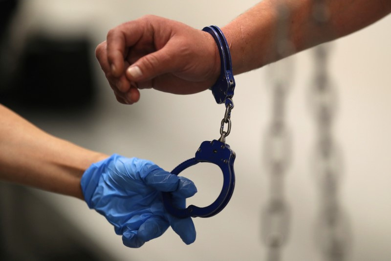 © Reuters. FILE PHOTO: A U.S. Immigration and Customs Enforcement's (ICE) Fugitive Operations Agent takes handcuffs off before booking an immigrant, March 1, 2020. REUTERS/Lucy Nicholson/File Photo