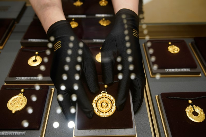 © Reuters. FILE PHOTO: A salesperson poses with Heritage Gold jewellery at jeweller Chow Tai Fook’s retail store in Shanghai, China August 18, 2021. REUTERS/Aly Song/File Photo