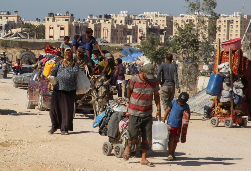 © Reuters. Displaced Palestinians make their way, as they flee Hamad City following an Israeli evacuation order, amid the Israel-Hamas conflict, in Khan Younis in the southern Gaza Strip, August 16, 2024. REUTERS/Hatem Khaled