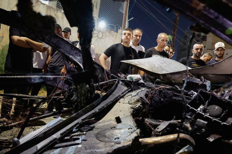 &copy; Reuters. Palestinians gather around a car damaged in an Israeli airstrike, in Jenin, in the Israeli-occupied West Bank, August 17, 2024. REUTERS/Raneen Sawafta