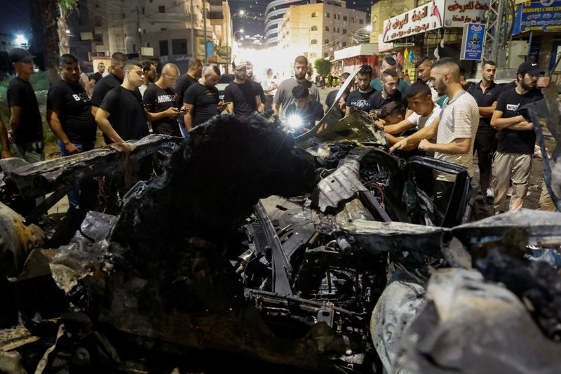 © رويترز. فلسطينيون يتفقدون سيارة تضررت في غارة جوية إسرائيلية في جنين بالضفة الغربية التي تحتلها إسرائيل في 17 أغسطس 2024. تصوير: رنين صوافطة - رويترز.